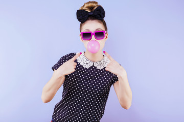 Portrait humoristique d'une jeune femme, ses doigts pointés vers la bulle de chewing gum