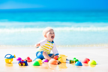 Baby playing on tropical beach digging in sand