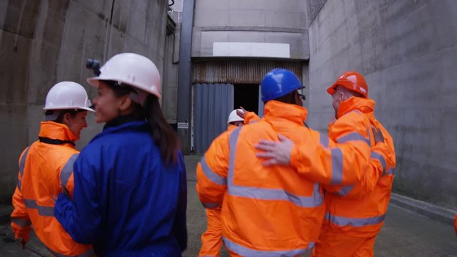  Team of workers at fuel plant come up from underground & walk into daylight