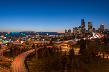 Seattle Freeway Skyline at dusk as cars leave light trails on the interstates which provide access to Washington State's largest city