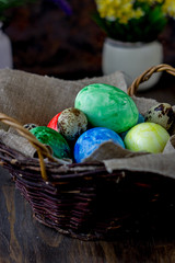 Colored easter eggs on basket over rustic table.