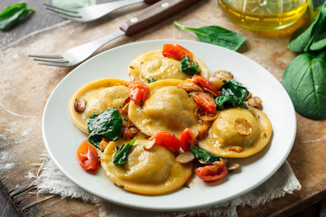 Ravioli with spinach and mushrooms on a wooden background