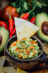 Guacamole with corn chips - nachos, made from avocado, tomatoes and lime.