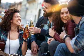 Group of young people hangout  on street in downtown.They standing by the city square,drinking and playing guitar.