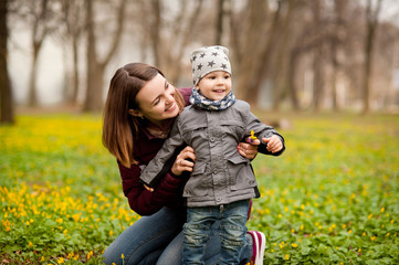 Mom and son with a small child are walking in a spring forest or park, mother's day
