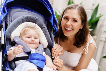 Mother walking with a baby pram (stroller, carriage) in town. Love and family concept.