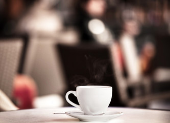 White cup of coffee at the summer cafe table