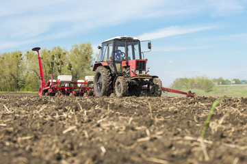 tractor with planter in the field on a background of blue sky