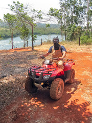 Man with kerchief on face sits on quad bike against Victoria Nile River background. Jinja, Uganda, Eastern Africa.    © shujaa_777
