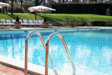 Shiny chrome ladder in the pool with blue water