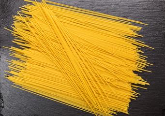 Raw spaghetti on a plate of black stone.