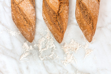 Rye and wheat bread with flour on white marble
