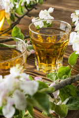 Apple juice in a glass with apple flowers on the table