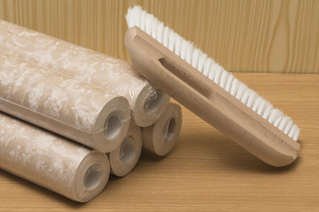 Several rolls of wallpaper and a brush for applying glue