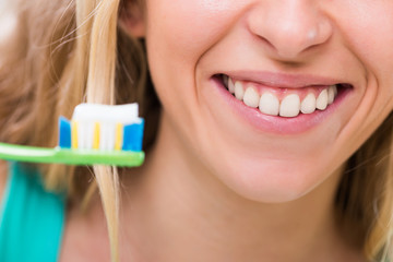 Woman with beautiful healthy white teeth using toothbrush