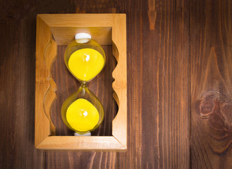 wooden retro sand glass clock lie on side with sand on wooden background. time stop concept.