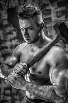 athlete and hammer. guy with a nice toppless muscle fitness body, bodybuilder coach hold big metal hammer