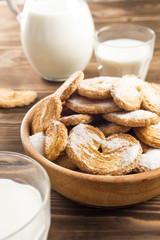 cookies in a plate on a table near the milk