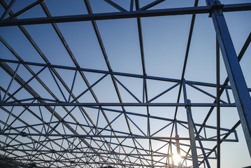 Galvanized steel roof truss construction frames with setting sun in the background
