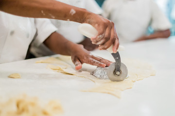 Woman's hands working : cutting dough in a restaurant kitchen