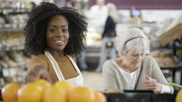  Friendly worker in a supermarket assisting senior lady buying groceries