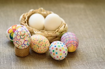 Easter eggs in a wicker basket on the tablecloth of burlap
