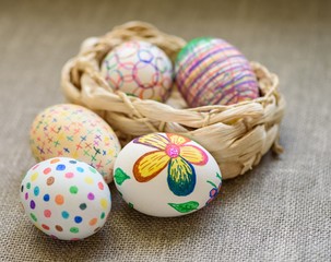 Easter eggs in a 1 wicker basket on the tablecloth of burlap