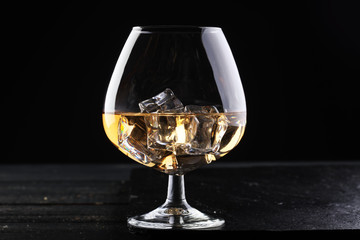 glass of whiskey with ice on a wooden