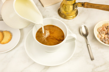 Milk poured into cup of coffee