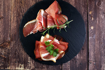 Bread with slices jamon serrano for lunch table. Sharing antipasti on party or summer picnic time...