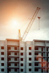 Construction crane and a building house on sunset background