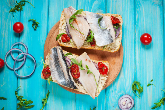sandwich with herring and onion on blue wooden table
