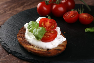 Fototapeta na wymiar Bread with cream cheese and tomato for lunch table. Sharing antipasti on party or summer picnic time over wooden rustic background.
