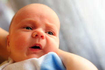 Cute baby girl makes a funny upset face on mothers hand