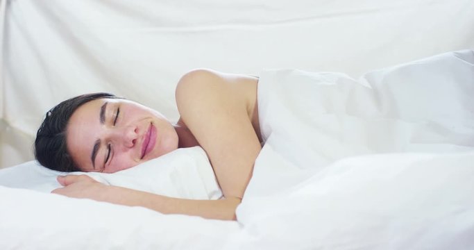 A simple day off for a beautiful young girl sleeping in a warm bed, covered with a soft  warm white blanket, on a white background.