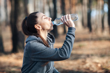 Close up portrait of a fit young woman drinking water after workout