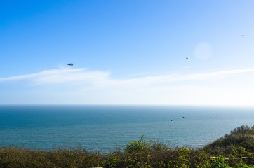 Coastguard helicopter and a flock of birds over the English Channel, UK