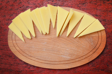 Pieces of cheese on the wooden board, top view
