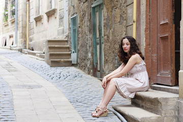 Fototapeta na wymiar Young girl on narrow streets wearing biege dress