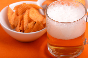 Glass of light beer and potato chips on a abstract background