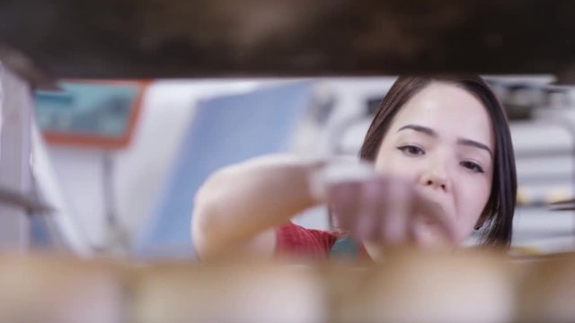  Worker in bakery kitchen counting bread batch & loading trays onto rack