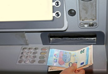 boy who withdraws money from an ATM machine in euro banknotes