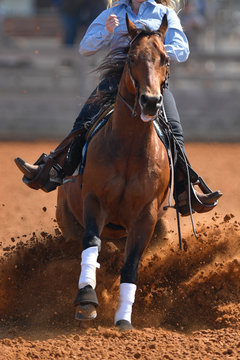 A front view of western rider sliding the horse in the dirt