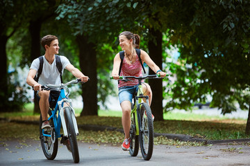 Young people, couple with bicycles in the park. A loving couple on a date on a summer evening. The...