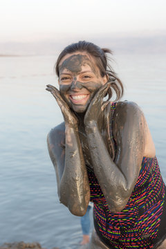 Portrait of beautiful girl applying Dead Sea mud body care treatment in Israel