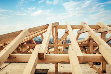 Installation of wooden beams and timber at construction site. Building the roof truss system structure of new residential house
