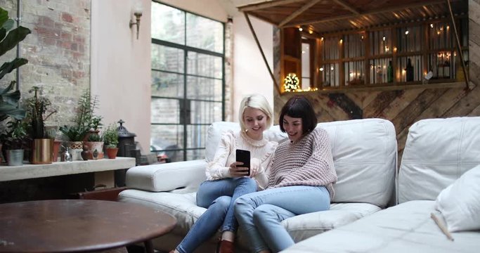 Young adult female friends looking at smartphone at home