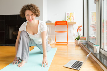 Fototapeta na wymiar Woman doing yoga with online app on computer in her living room