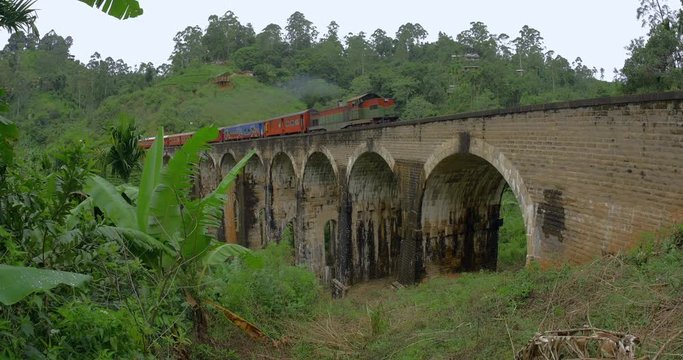 Train passing famous Nine Arches Bridge in Sri Lanka near Demodara and Ella. Iconic tourist landmark and tourist travel destination attraction