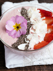 Strawberry, Banana Smoothie Bowl, garnished with sliced strawberry, chia seeds, coconut flakes, edible primula flower